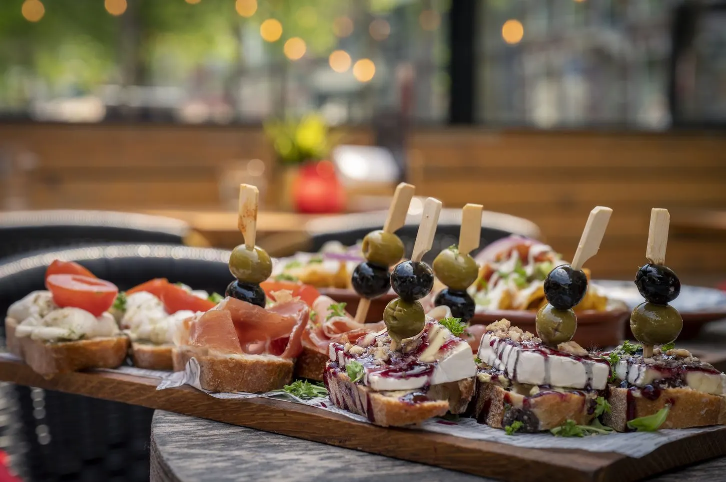 Plank met pintxos: olijven, ham en kaas op geroosterd brood