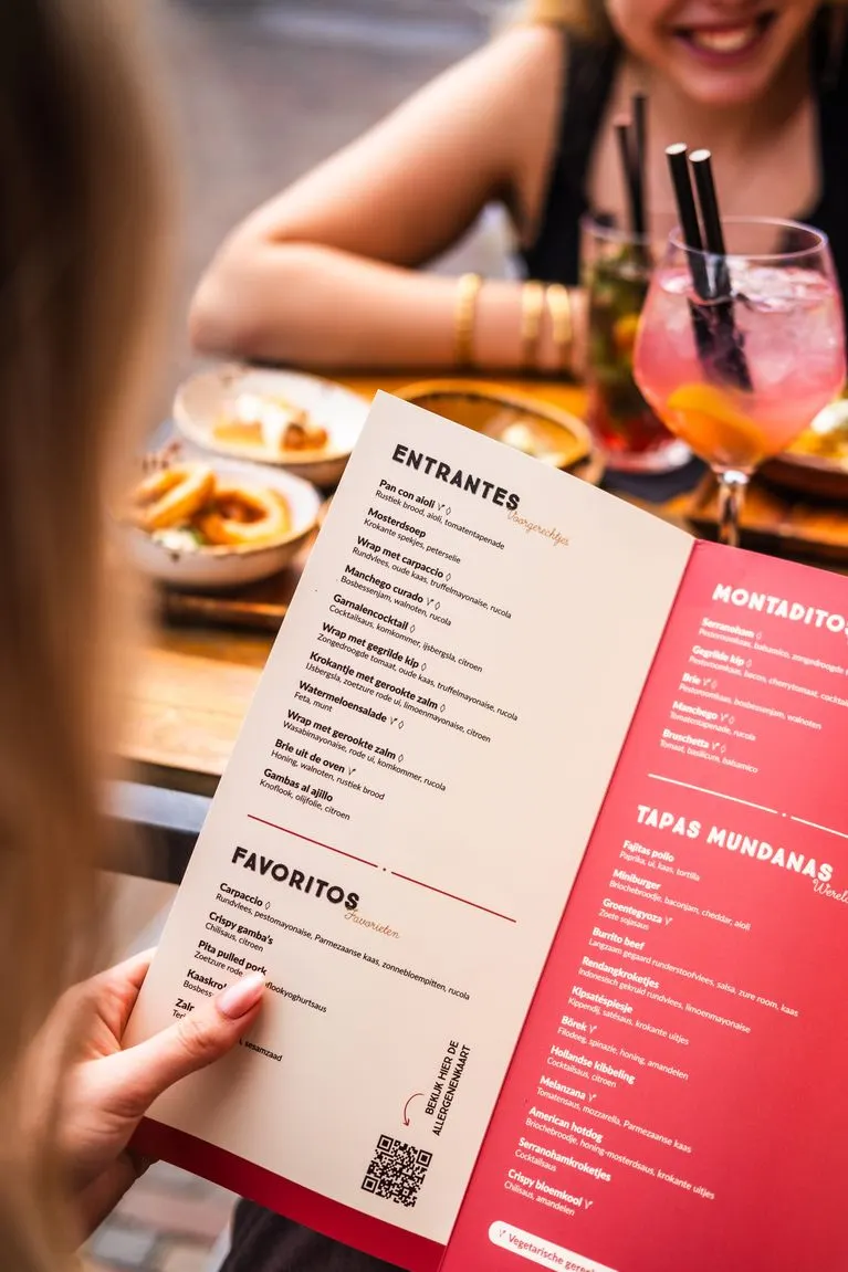 De tapaskaart van Pata Negra in de hand, met een cocktail op de achtergrond