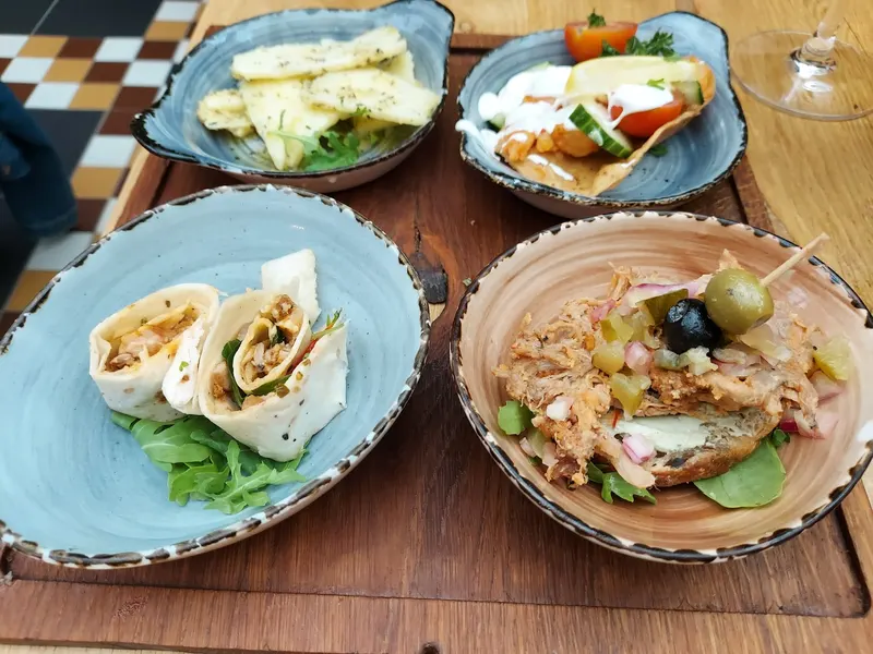 Vier tapas op blauwe schalen: wraps, aardappel en een montadito