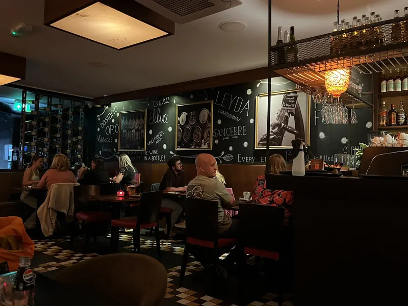 De bar met krijtborden, gasten aan tafel in warm avondlicht