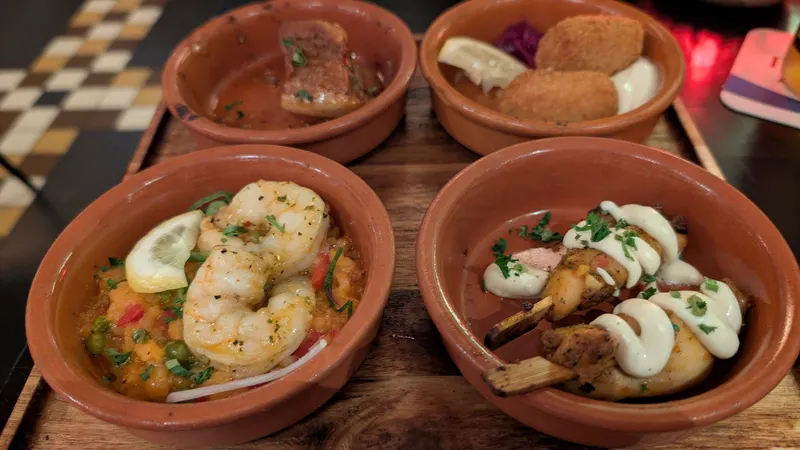 Terracotta schaaltjes met gamba's en kip op een geblokte tafel
